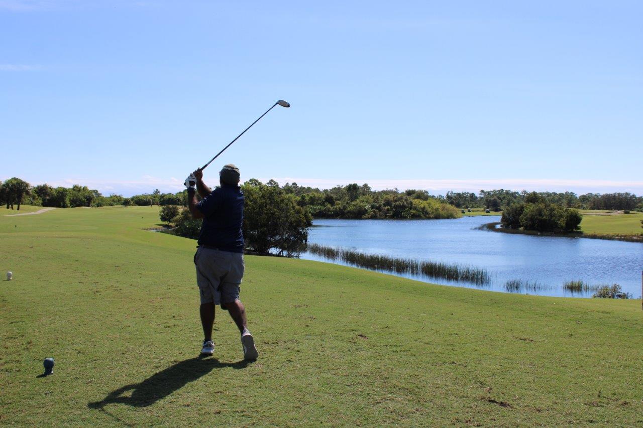 Dr. Ashish Udeshi is seen from behind, mid-golf-swing